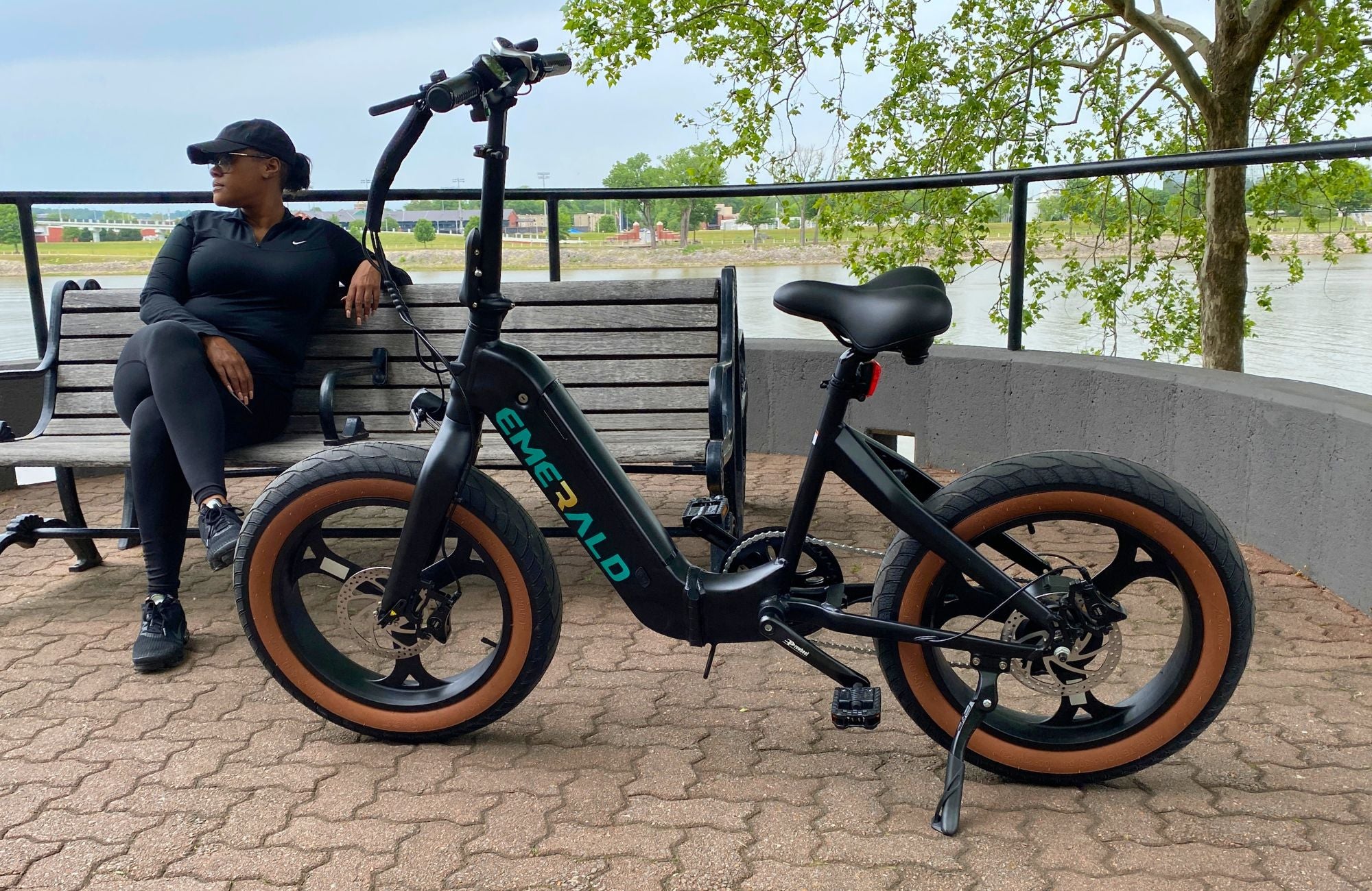 Woman resting on bench behind parked Emerald ebike