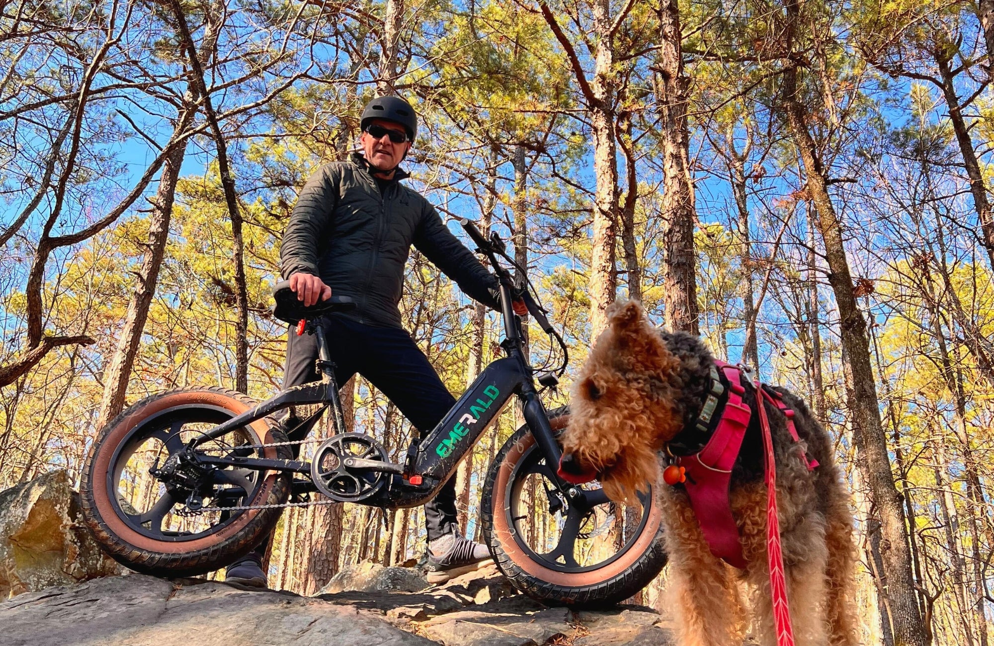 The Emerald Bike being driven on a biking trail next to a dog on a leash